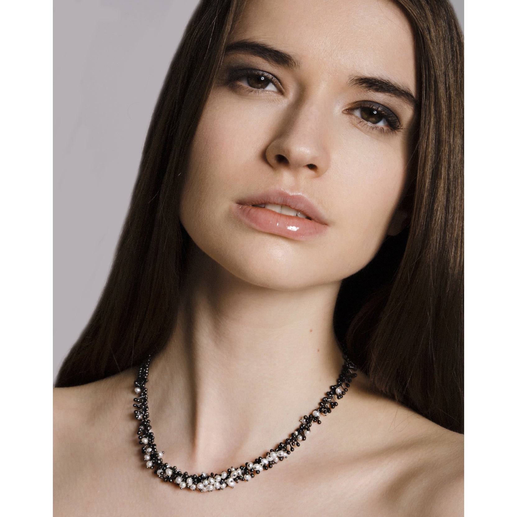 Model wears a handmade oxidised silver and freshwater pearl necklace. The chain is made up of hundreds of handmade silver droplets. 