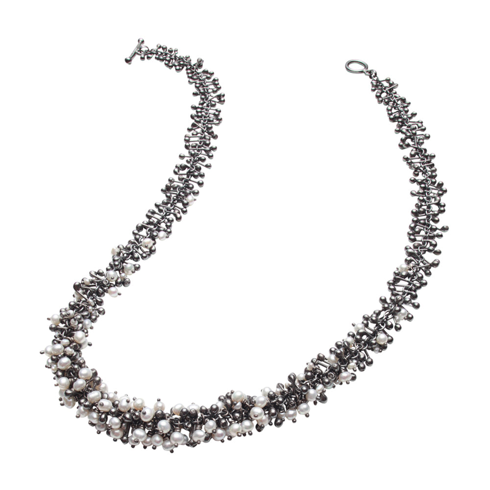 A handmade oxidised silver and freshwater pearl necklace. Beads and droplets of pearl and silver form a dense cluster necklace.